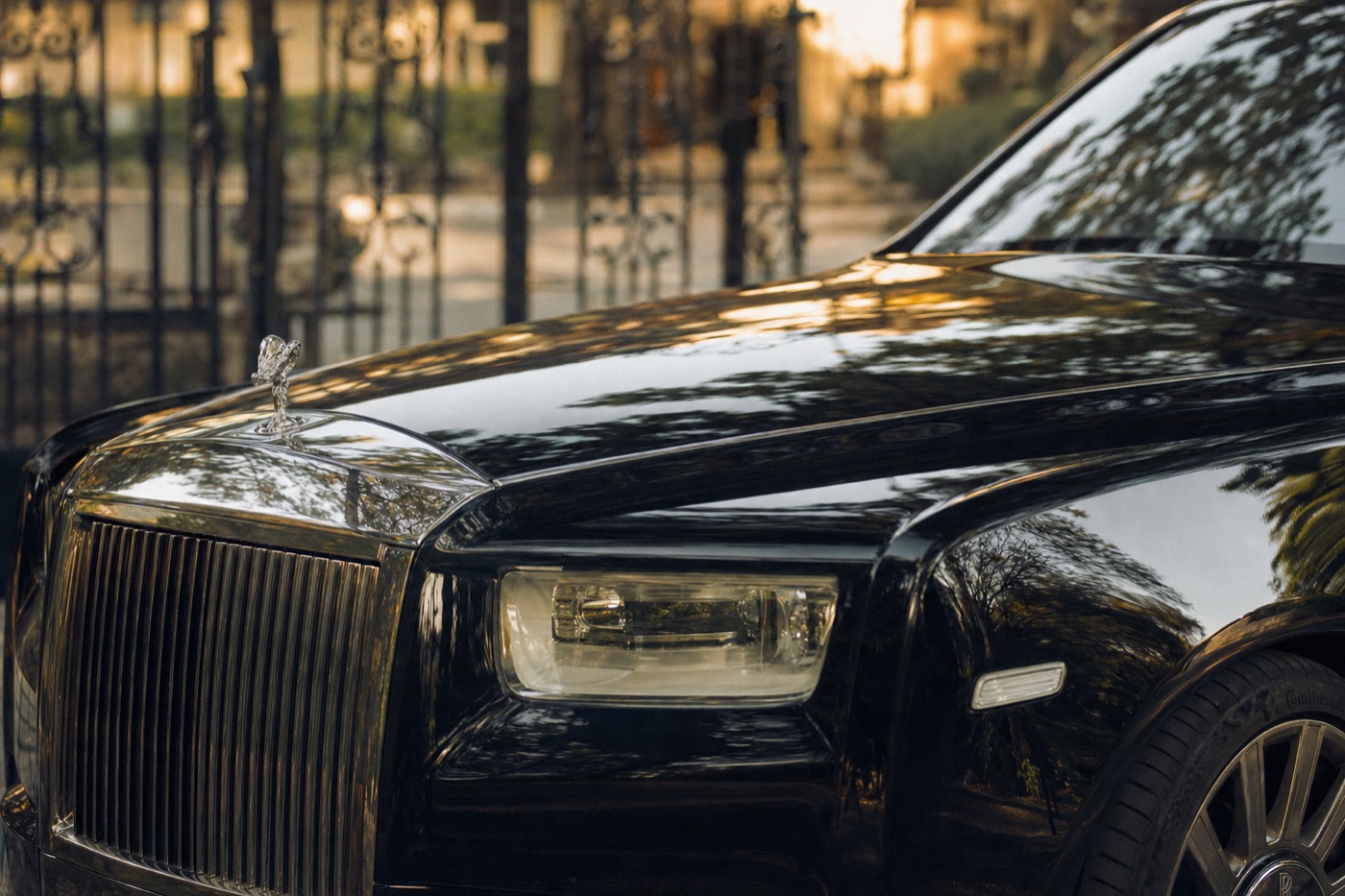 Wedding exotic car rental timeline: the Spirit of Ecstasy ornament on a black Rolls-Royce Phantom in warm evening light