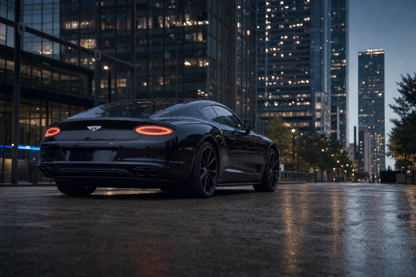 Houston exotic car rental: a black Bentley Continental GT on an empty wet street beneath downtown glass towers at blue hour