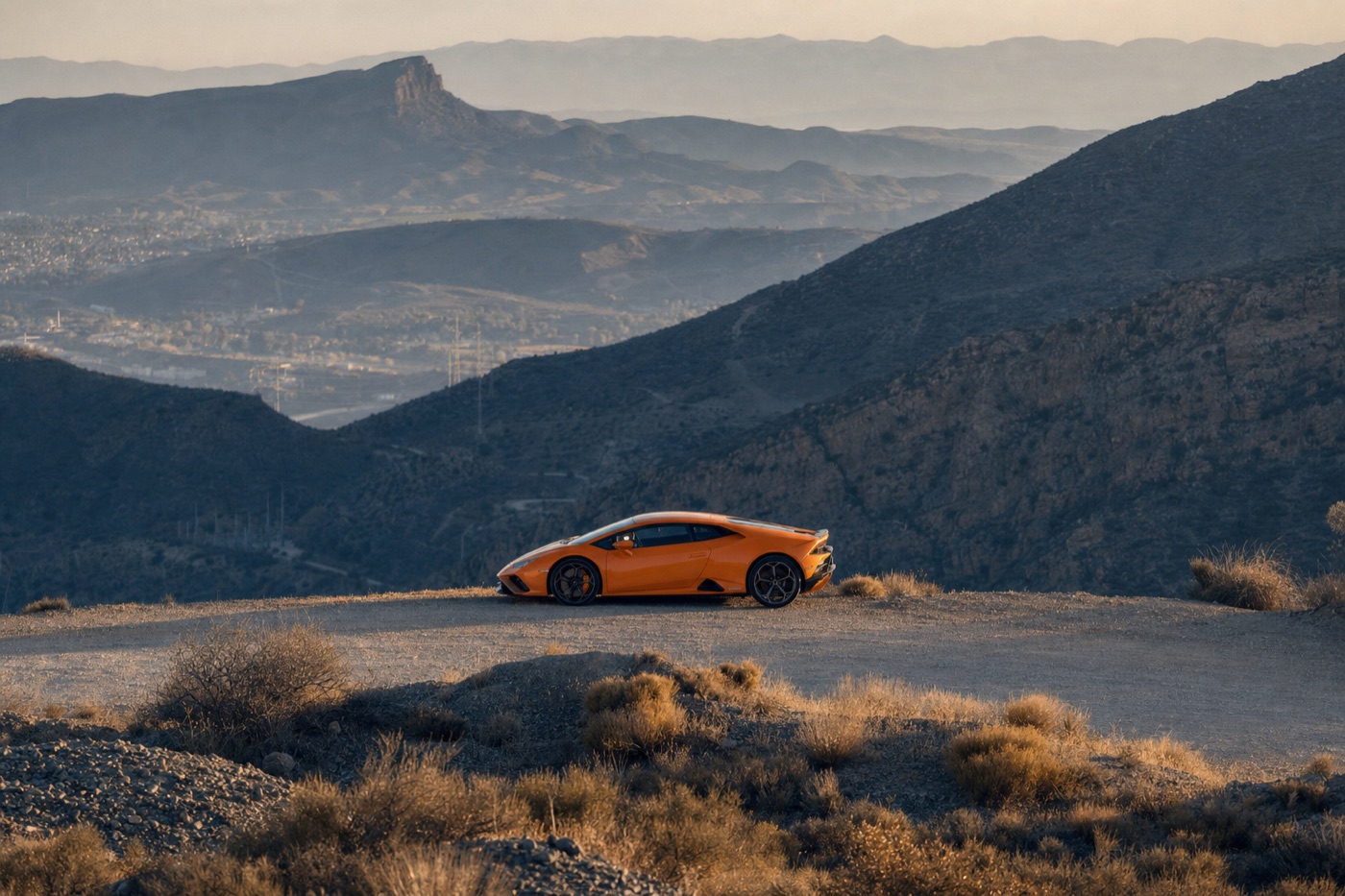 Lamborghini Huracán rental guide: an orange Huracán EVO coupe parked on a gravel desert overlook at sunrise