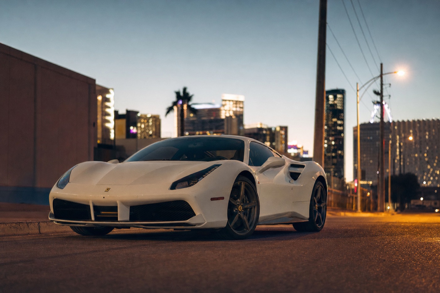 Las Vegas supercar rental: a white Ferrari parked on a side street at dusk with blurred casino lights behind