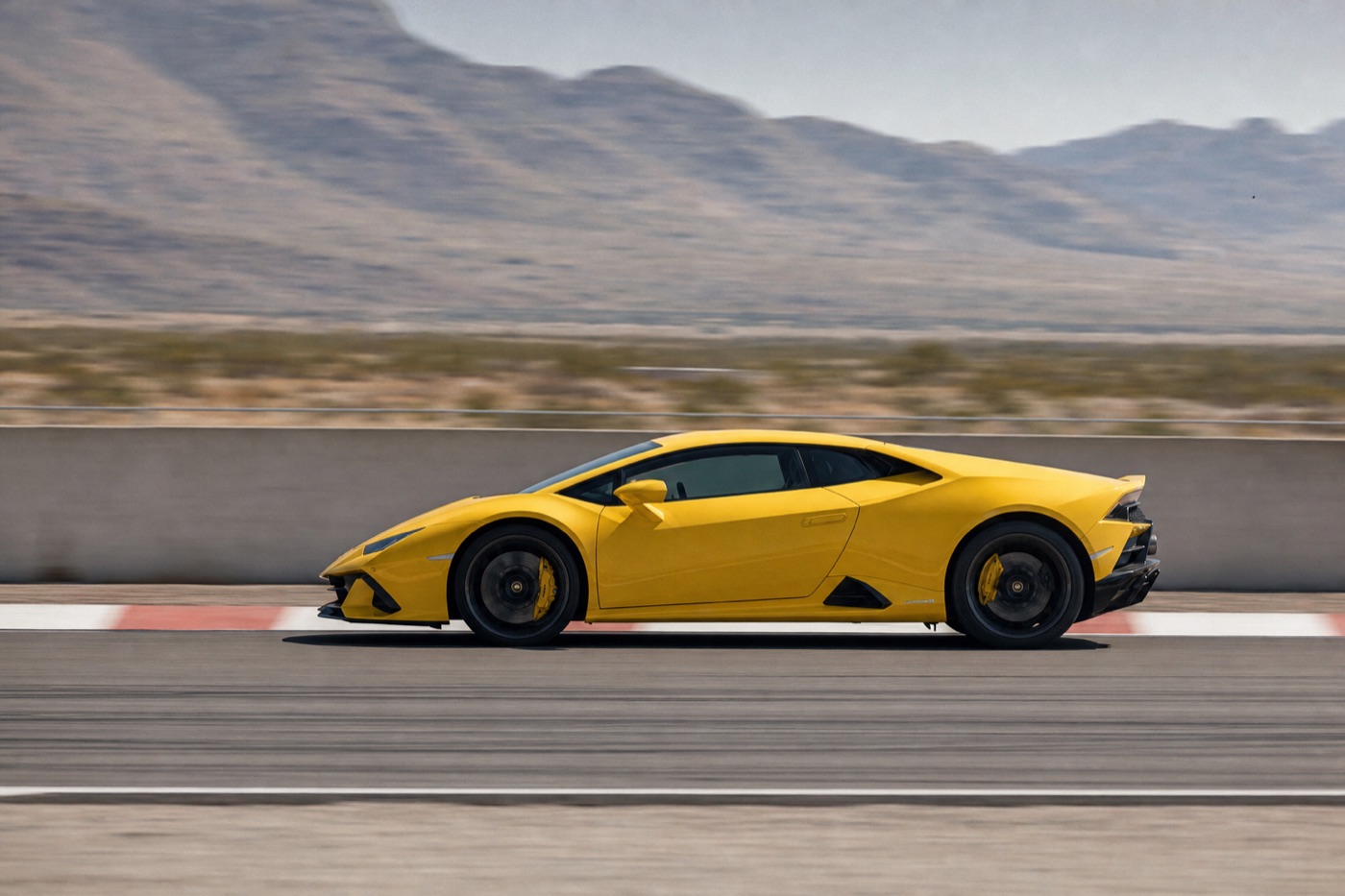 Las Vegas supercar driving experience: a yellow Lamborghini Huracán on a race circuit straight beside a concrete pit wall