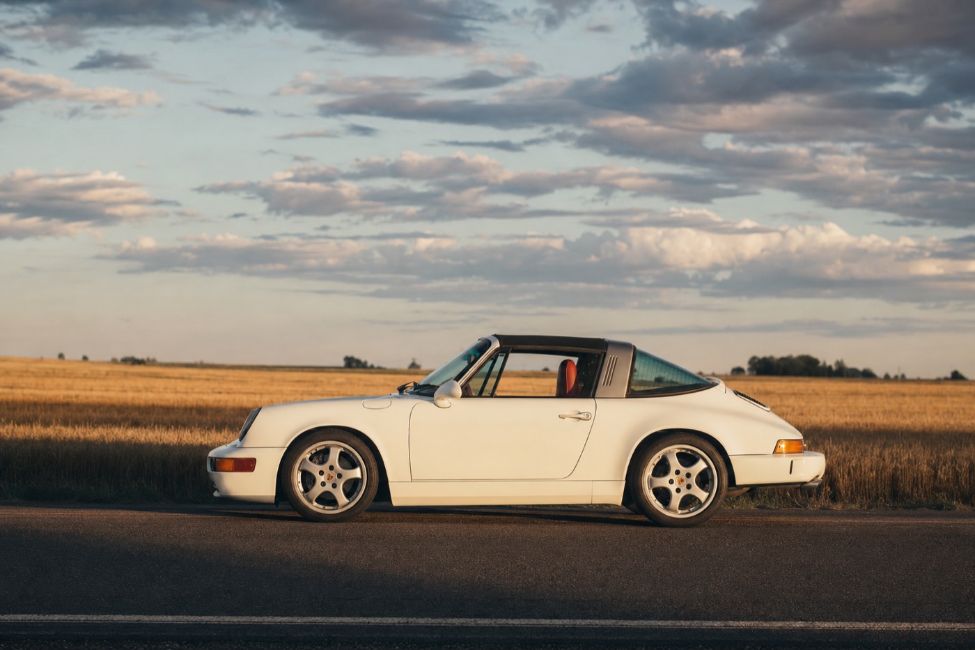 Where Porsche rentals are available: a Porsche 911 on a prairie highway under big sky