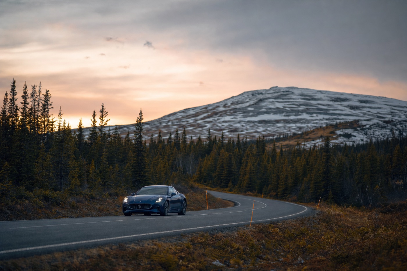 A rare exotic rental in the far north: a Maserati on a remote highway among spruce forest and snow-dusted hills