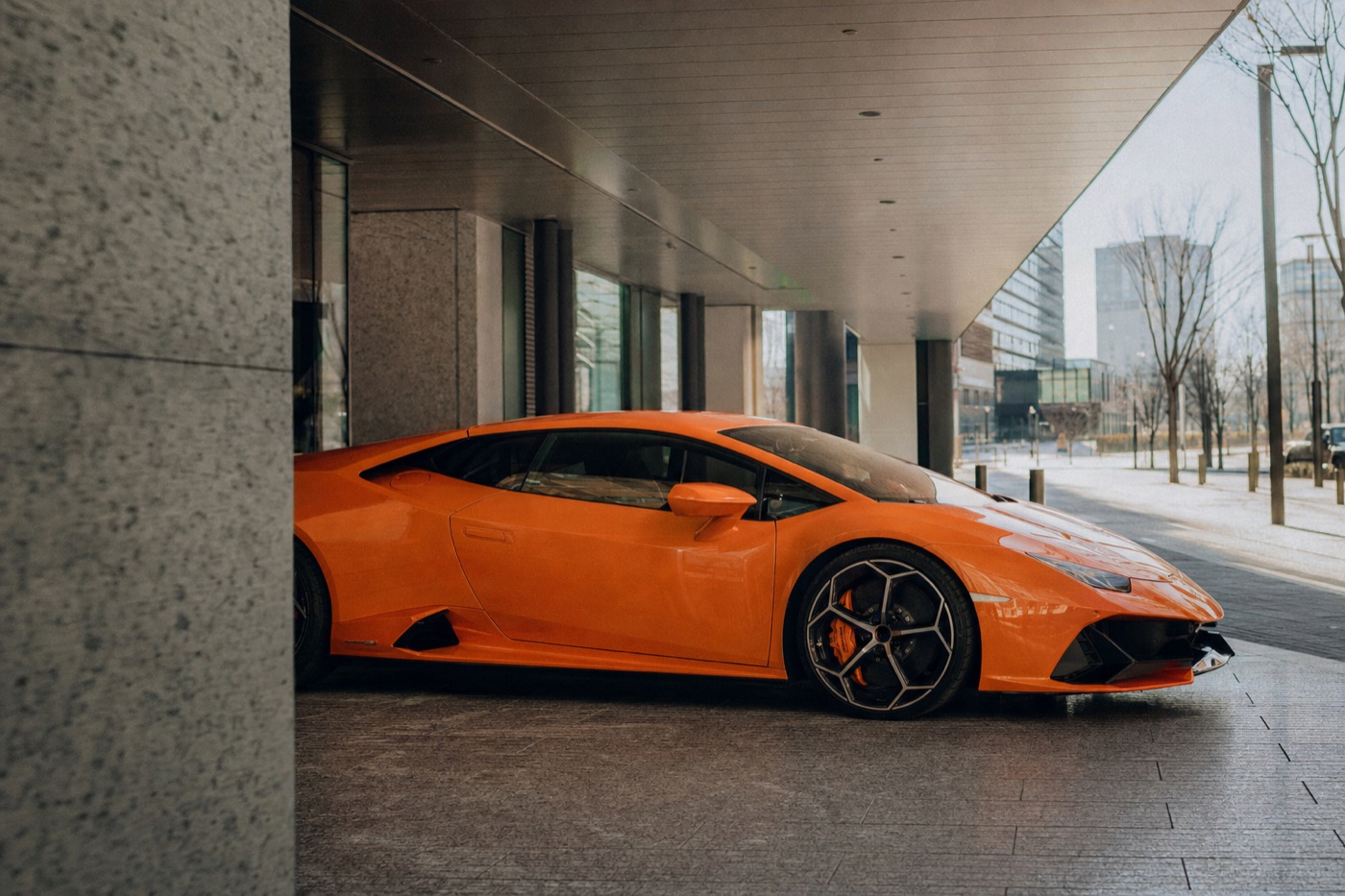 The real cost of renting an exotic car: an orange Lamborghini Huracán waiting under a building canopy