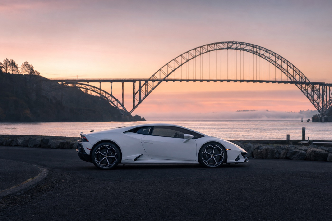 Supercar rental prices compared: a white Lamborghini Huracán EVO parked by a harbour bridge at dawn